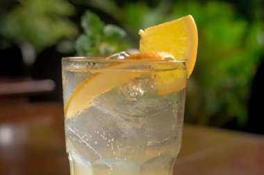 Tahta masada buzlu ve limonlu bir bardak portakal suyu..