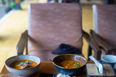 Tahta bir masada tavuk ve sebzeli Tayland çorbası.