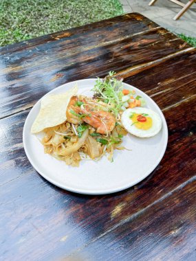 Tayland usulü yumurta, pirinç eriştesi ve ahşap masada sahanda yumurta.