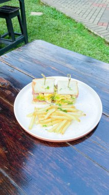 Peynirli sandviç ve ahşap arka planda salata.