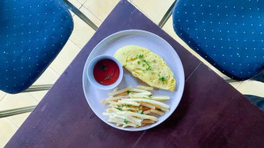 Kızarmış yumurta, patates kızartması, salata ve ketçap.