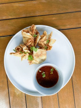 Sebzeli kızarmış tavuk kanadı ve beyaz tabakta sos.