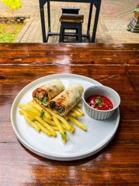 Lezzetli ve lezzetli bir patates kızartmasının dikey görüntüsü ahşap bir masada.