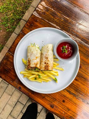 Sebzeli kızarmış balık rulosu ve ahşap masada sos.