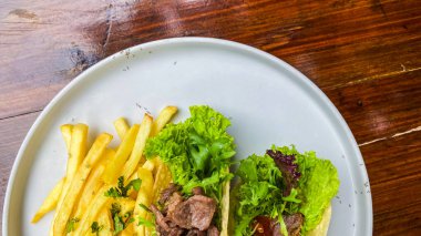 Tabakta patates ve sebzeli kızarmış biftek. Beyaz tabakta patates kızartması..