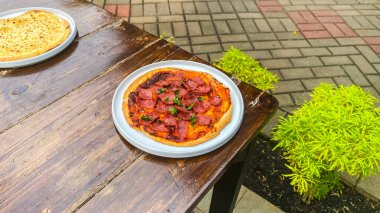 Tahta bir masada etli ev yapımı bir pizza kasesi.