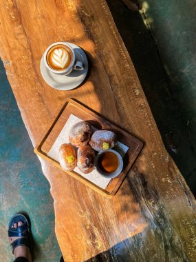 bir fincan kahve ve bir parça çikolata ahşap bir masada.