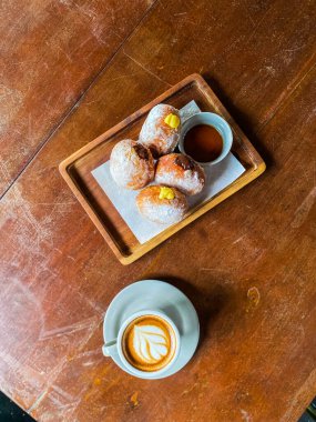 Tahta bir masada bir fincan kahve ve iki ay çöreği.