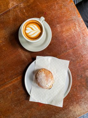 Tahta masanın üzerinde çörekle bir fincan kahve..