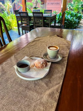 Kahve dükkanındaki masada bir fincan kahve ve bir kruvasan..