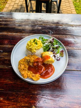 Ahşap masada pilavlı ızgara tavuk.