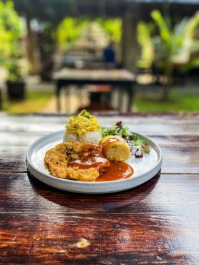 Bir tabak lezzetli kızarmış tavuğun dikey yakın çekimi. Bir parça buz ve bir parça ekmek.