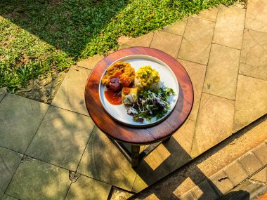Bahçedeki bir evin terasında tabağı ve salatası olan leziz bir kızarmış tavuğun yakın çekimi.