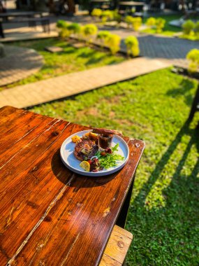Masanın dikey yakın çekimi. Bir tabak lezzetli et, masada servis edilmiş ve kızarmış tavuk.