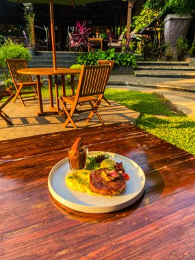 Bahçe masasında sebzeli ızgara biftek.