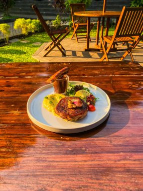 Bahçe masasında sebzeli ve soslu ızgara et.