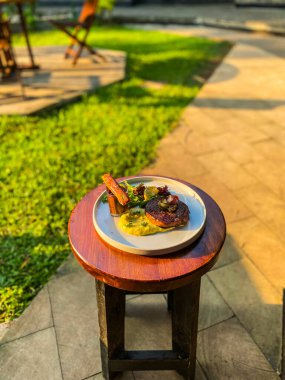 Bir tabak yiyecek ve sebzeyle tahta bir masanın dikey görüntüsü.