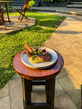 Bahçedeki ahşap masada sebzeli ızgara domuz eti..