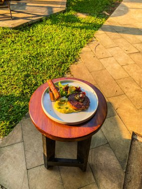 Bahçede bir tabak ve bir bardak birayla bir masanın dikey görüntüsü.