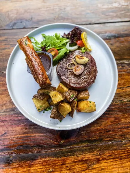 Sebzeli ızgara biftek ve ahşap arka planda sos.