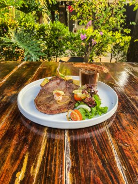 Ahşap bir masada ızgara etli biftek.