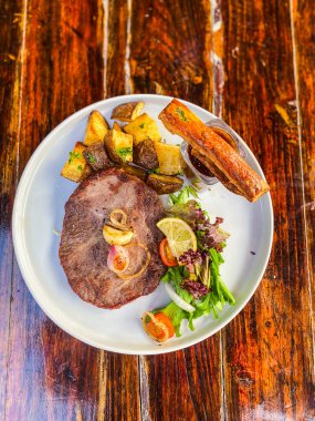 Biftek ile patates, mantar ve ızgara sebze beyaz tabakta, üst manzara, kapat.