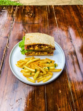 Kızarmış sandviç, patates kızartması, peynir, marul ve soğan.