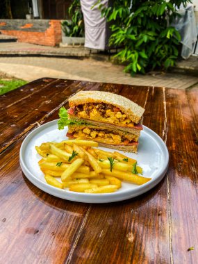 Tahtada patates kızartması ve ızgara tavuklu sandviç.