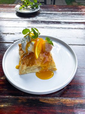 Bir dilim kremalı turta ve ahşap bir masada taze meyveler.