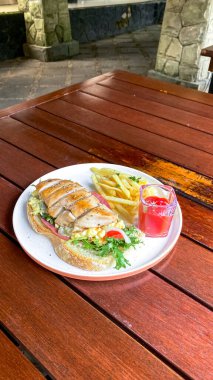 Patates kızartması ve bir bardak su ile yüksek açılı bir sandviç manzarası.