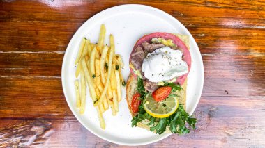 Lezzetli bir sandviçin ve ahşap bir masada kızarmış patatesin yüksek açılı çekimi.