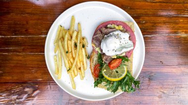 Somon balıklı kızarmış patates ve tahta tabakta salata.