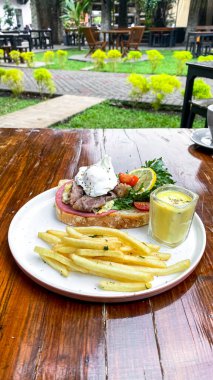 Kahvaltı omlet ve kızarmış yumurtalı tost ve ahşap masada salata.