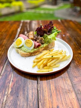 Tahta bir masada biftek ve sebzeli sandviç.