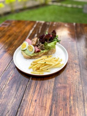 Tahta arka planda tavuk eti ve sebzeli bir sandviç.