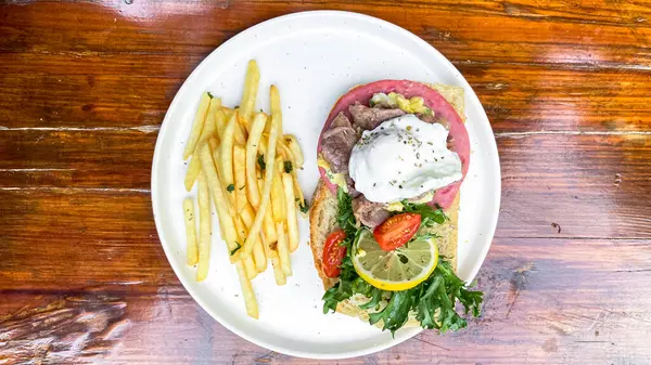 Lezzetli bir sandviçin ve ahşap bir masada kızarmış patatesin yüksek açılı çekimi.