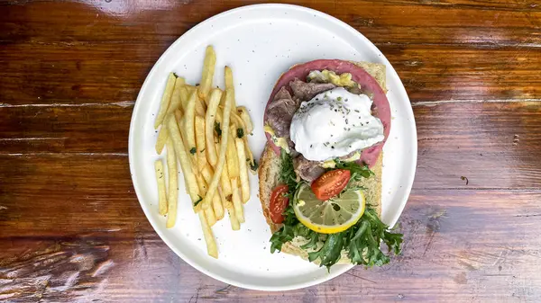 Somon balıklı kızarmış patates ve tahta tabakta salata.