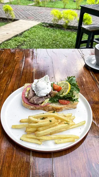 Kızarmış patates, kızarmış et ve peynirli bir tabak sandviçin dikey çekimi.