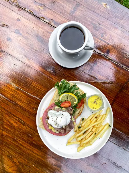 Tahta bir masada kızarmış balık, peynir ve kahve ile bir tabak taze sandviç..