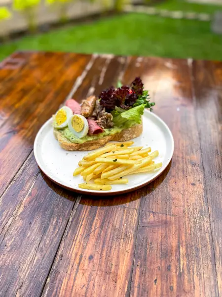 Tahta arka planda tavuk eti ve sebzeli bir sandviç.