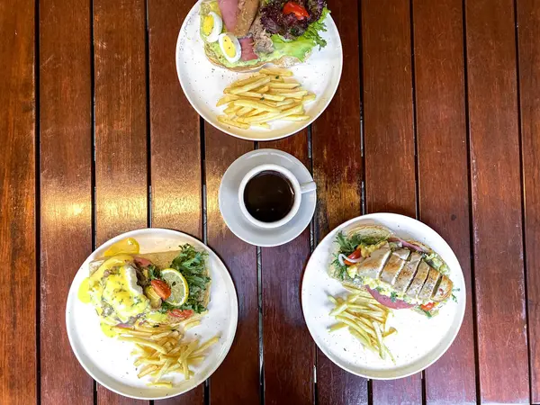 Restoran masası ve restoran yemeği olan ahşap bir masanın üzerindeki çeşitli tabakların üst görüntüsü.