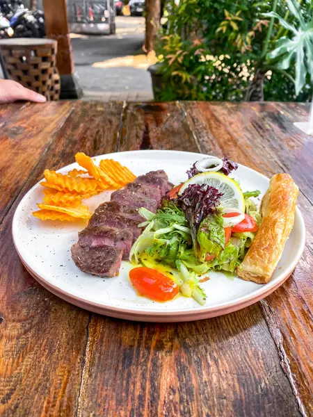 Salatalı biftek ve ahşap tabakta kızarmış patates.
