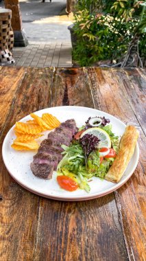 Izgara sebzeli biftek, kızarmış patates ve salata.