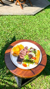 Bir tabak lezzetli sığır burger ve bir bardak meyve suyuyla ızgara biftek.