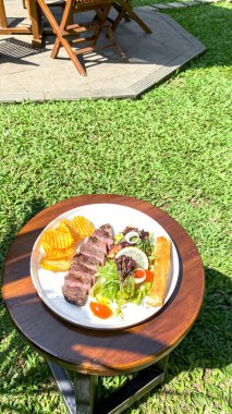 Doğadaki ahşap masada ızgara sebzeli biftek..