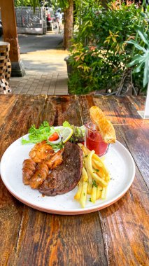 Sebzeli ızgara biftek ve tahta tabakta salata.