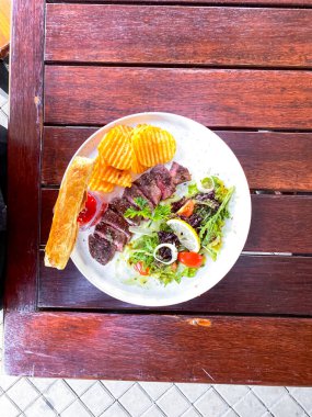 Bir tabak kızarmış balık, patates kızartması, limon ve salata.