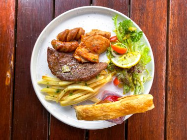 Ahşap masada sebzeli ızgara biftek.