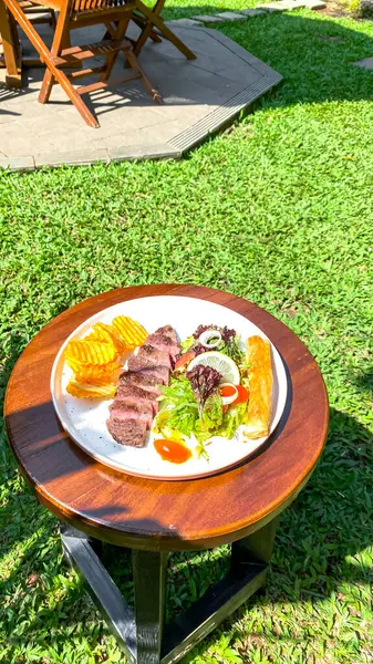 Bahçede salata ve sebzeli ızgara biftek.