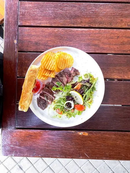 Bir tabak kızarmış balık, patates kızartması, limon ve salata.